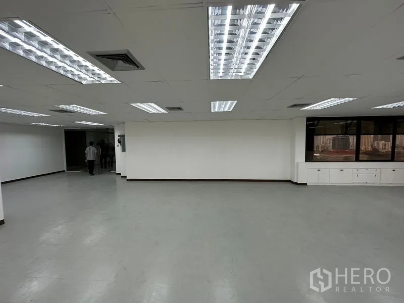Office Space for rent in Watthana, Bangkok - Open office area with white walls, recessed lighting, corner windows with urban views and built-in storage.