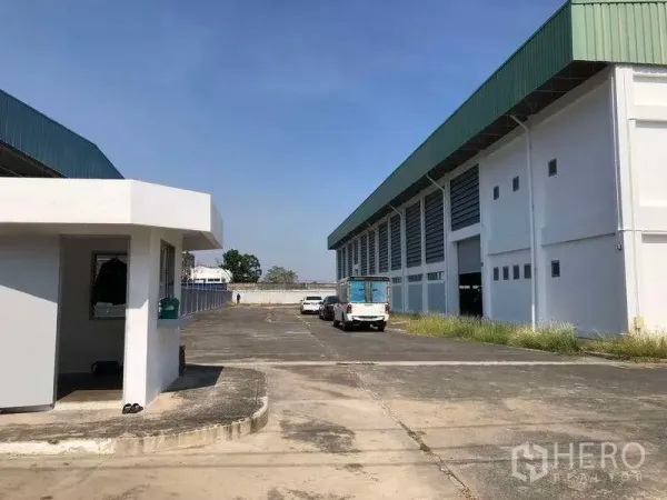 Factory for rent or sale in Phra Nakhon Si Ayutthaya - Security gatehouse and wide access road with on-site parking beside the factory building.