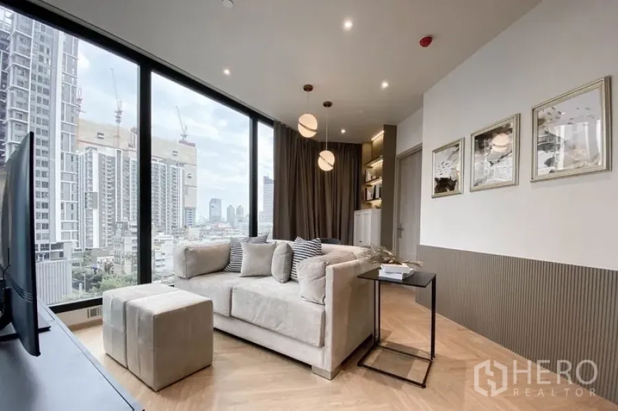 公寓 出租在Din Daeng, Bangkok - 客厅采光充足，落地窗与城市天际线景观，米色沙发与吊灯。