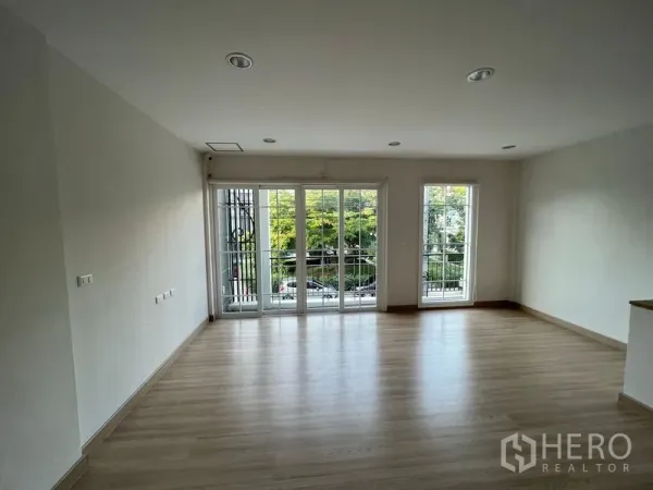 Home Office for rent or sale - Bright upper-floor room with wood flooring and full-height windows to a balcony overlooking greenery.