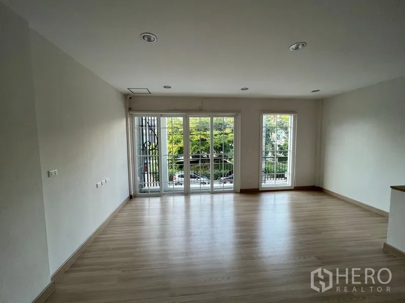 Home Office for rent or sale - Bright upper-floor room with wood flooring and full-height windows to a balcony overlooking greenery.