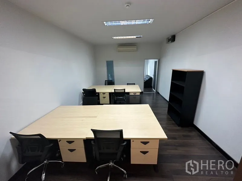 Office Space for rent in Khlong Toei, Bangkok - Open-plan workspace with multiple desks, task chairs, bookshelf and ceiling lighting on dark wood floors.