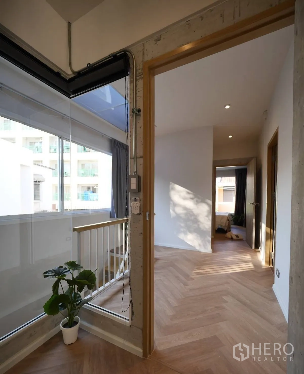 Townhouse for rent or sale in Watthana, Bangkok - Glass corner by the staircase with potted plant and herringbone floor.