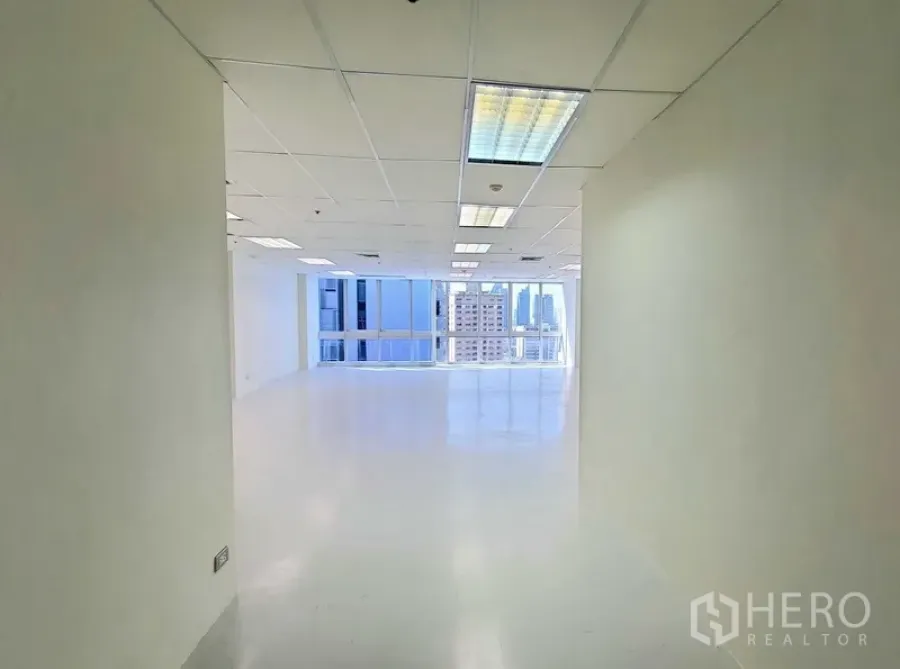 办公空间 出租在Khlong Toei, Bangkok - 明亮的入口走廊通向开放式办公区，白色地面、吊顶灯具与大窗户，可见曼谷天际线。