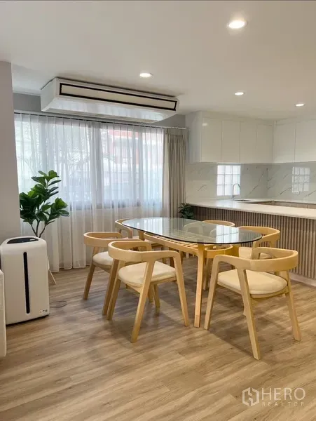Detached House for rent in Bang Rak, Bangkok - Bright dining corner with large windows, indoor plant, air-conditioning, and view to the sleek kitchen.