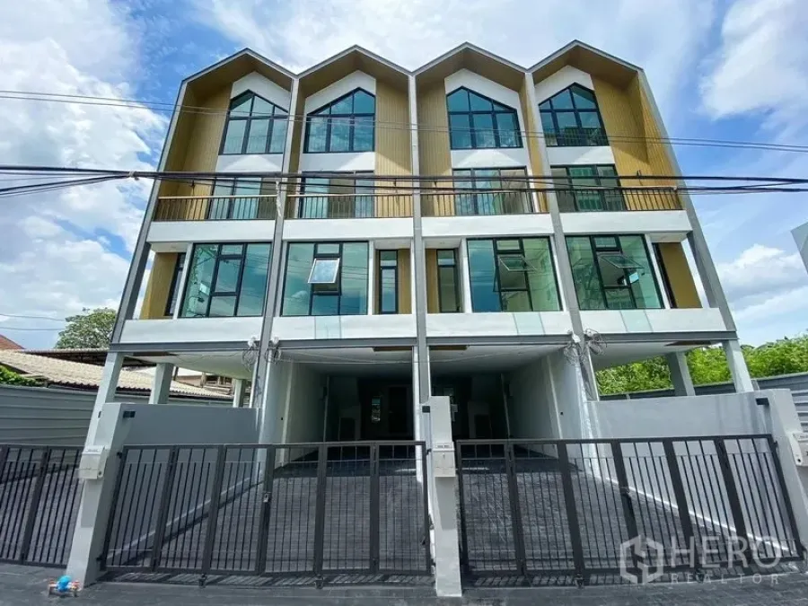 Home Office for rent or sale in Bang Na, Bangkok - Modern four-storey home office facade with gabled rooflines, full-height windows and gated parking area.