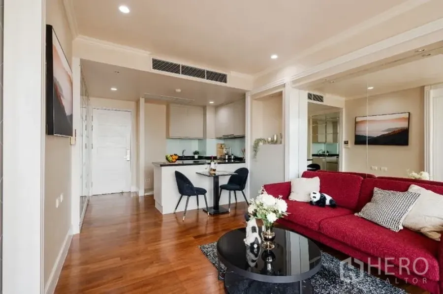Condominium for sale - Open-plan living area with red sofa, black coffee table and kitchen bar.