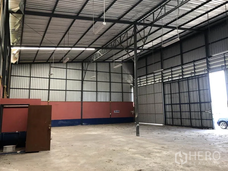 货栈 出租在Lam Luk Ka, Pathum Thani - 仓库内部视角，钢柱与屋架、超大滑门入口与开阔储存空间。