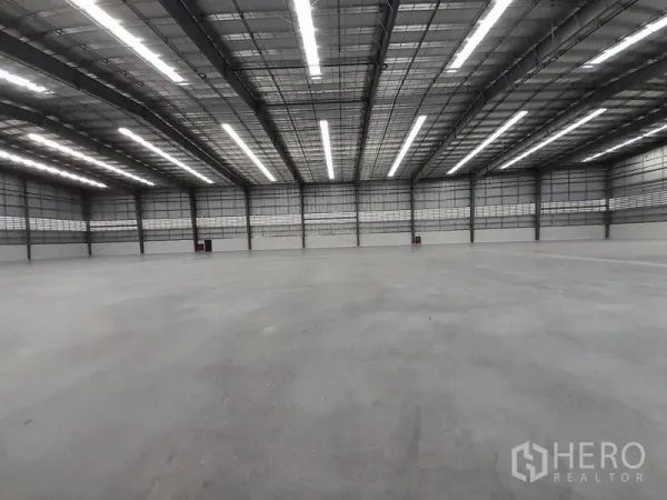 Factory for rent in Mueang Rayong, Rayong - Vast clear-span warehouse interior with high bay ceiling, LED strip lighting, and polished concrete floor.