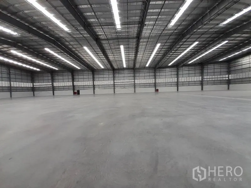 Factory for rent in Mueang Rayong, Rayong - Vast clear-span warehouse interior with high bay ceiling, LED strip lighting, and polished concrete floor.