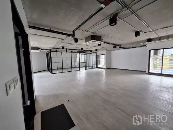 Office Space for rent in Watthana, Bangkok - Expansive office area with floor-to-ceiling windows and steel-framed glass meeting room.