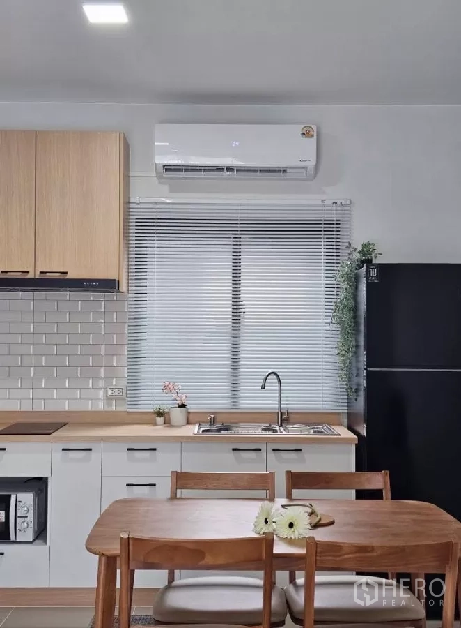 Townhouse for rent in Bang Phli, Samut Prakan - Dining area with wooden table for four, cooktop, cabinets and air-conditioning.