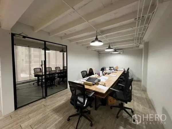 办公空间 出租在Pathum Wan, Bangkok - 工作区配长桌与办公椅，旁边为玻璃隔断会议室。