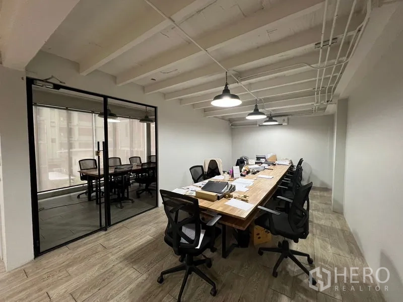 办公空间 出租在Pathum Wan, Bangkok - 工作区配长桌与办公椅，旁边为玻璃隔断会议室。