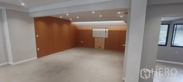 Office Space for rent in Watthana, Bangkok - Spacious room with wood-paneled accent wall and spotlights.