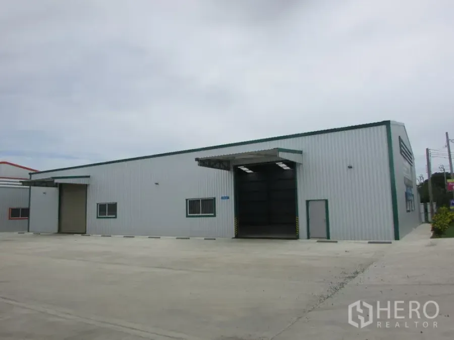 Warehouse for rent in Pak Kret, Nonthaburi - Front view of warehouse showing two loading doors and a large concrete yard for trucks.