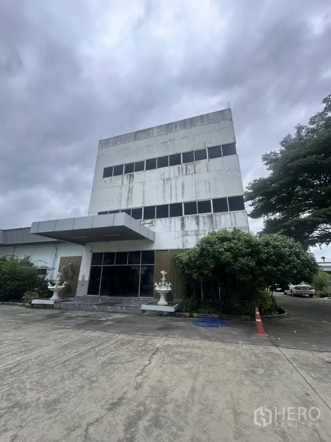 Factory for sale in Lat Krabang, Bangkok - Front view of three-storey factory office building with canopy and driveway.