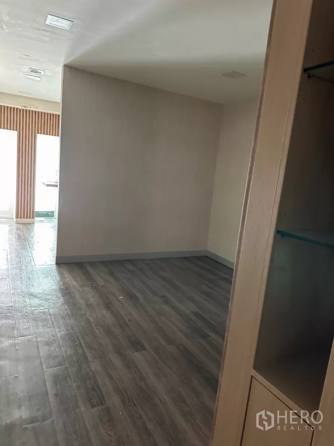 Shophouse for sale in Watthana, Bangkok - Private room with dark wood-look flooring and built-in shelving unit.