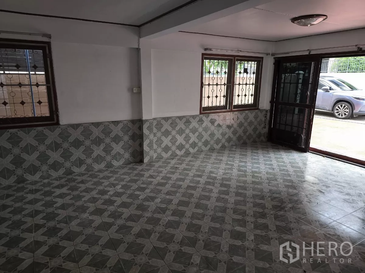 Home Office for rent in Wang Thonglang, Bangkok - Ground-floor living area with patterned tiles, security grilles and double doors opening to the driveway.