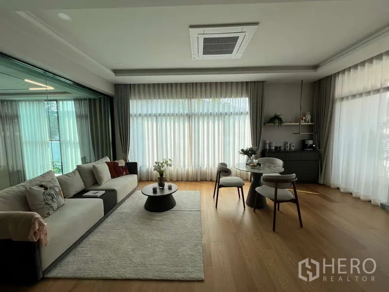 独立式住宅 出售在Suan Luang, Bangkok - 宽敞客厅，木地板、纱帘、沙发与茶几