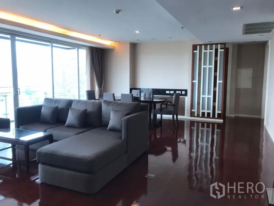 Apartment for rent in Khlong Toei, Bangkok - Spacious living and dining area with L-shaped sofa, polished floors and balcony doors in a Khlong Toei apartment.