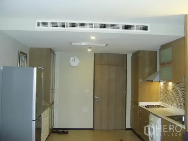 Condominium for rent in Khlong Toei, Bangkok - Entry and open kitchen with cooktop, range hood, mosaic backsplash and in-unit washing machine.