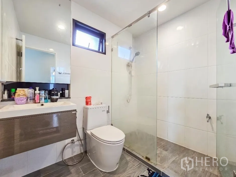 Detached House for sale in Lam Luk Ka, Pathum Thani - Bright bathroom with glass-enclosed shower, vanity and toilet.