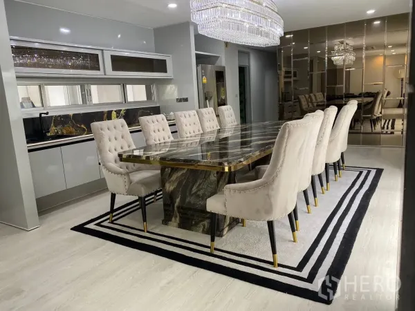 Detached House for rent in Suan Luang, Bangkok - Dining space with long marble table, tufted chairs and a mirrored wall.