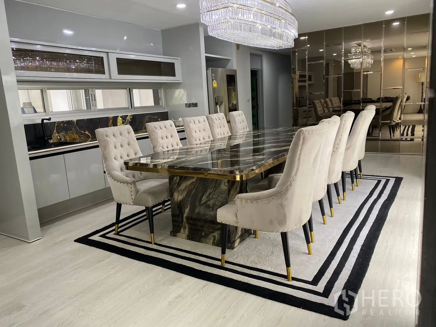 Detached House for rent in Suan Luang, Bangkok - Dining space with long marble table, tufted chairs and a mirrored wall.