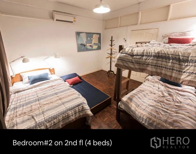 Townhouse for rent in Khlong Toei, Bangkok - Second-floor bedroom with multiple beds including a bunk bed, parquet floor and soft lighting.