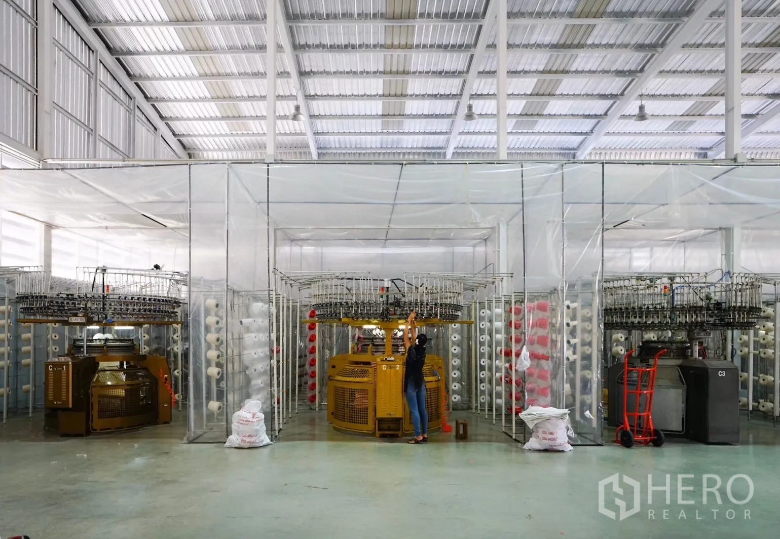 Factory for sale in Krathum Baen, Samut Sakhon - Circular knitting machines and yarn storage inside a transparent partitioned area.