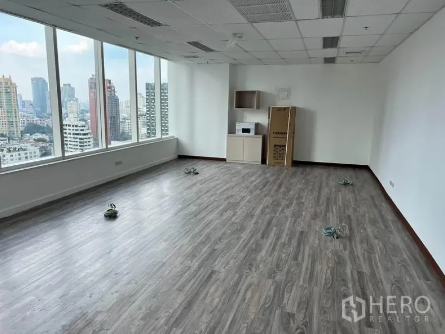 办公空间 出租在Watthana, Bangkok - 角落办公区配大面积窗户与小型茶水柜，享全景城市视野。