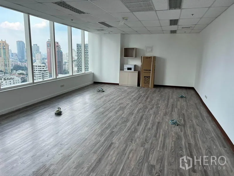 Office Space for rent in Watthana, Bangkok - Corner office zone with large windows, a small pantry cabinet, and panoramic skyline outlook.