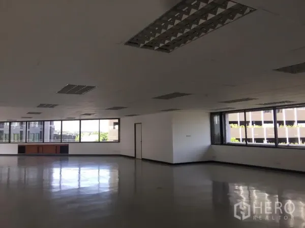 Office Space for rent in Bang Kapi, Bangkok - Corner section of office with wraparound windows and natural light overlooking nearby buildings.