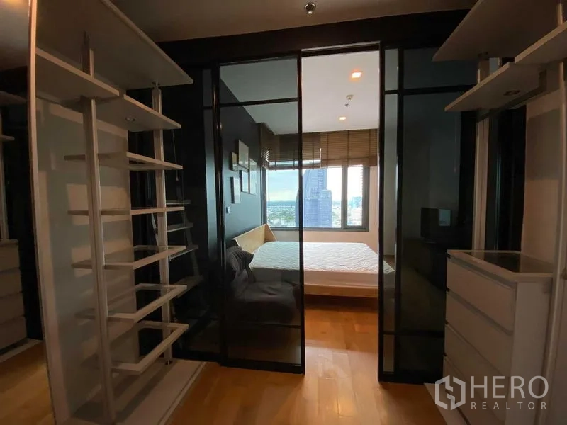 Condominium for rent in Khlong Toei, Bangkok - Walk-in closet featuring white shelving and sliding glass doors to the bedroom.