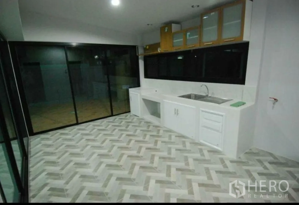 Home Office for rent in Lat Phrao, Bangkok - Bright kitchen with white built-in cabinets, sink and chevron tile flooring beside large sliders.