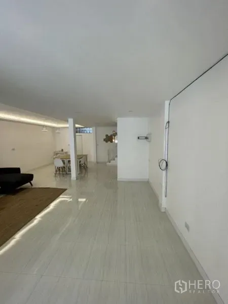 Townhouse for rent in Phra Khanong, Bangkok - Long, bright ground floor space with glossy tile flooring and white walls.