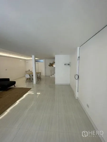 Townhouse for rent in Phra Khanong, Bangkok - Long, bright ground floor space with glossy tile flooring and white walls.