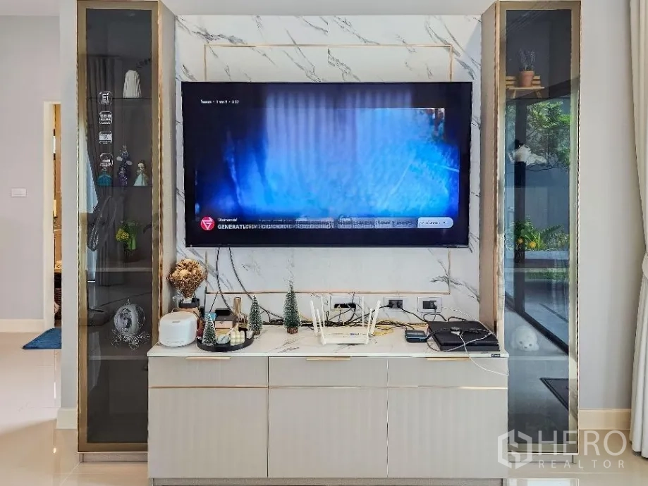 Detached House for sale in Lam Luk Ka, Pathum Thani - Close-up of marble feature wall with built-in TV cabinet and glass display shelves.