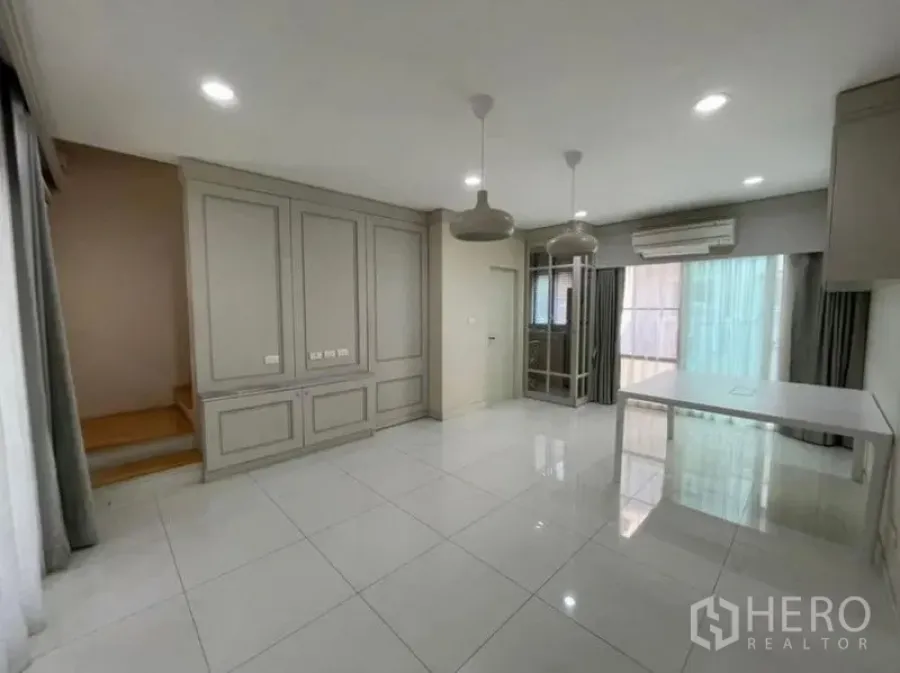 Townhouse for sale - Ground-floor living–dining space with staircase, air-conditioning, and sliding doors to the terrace.