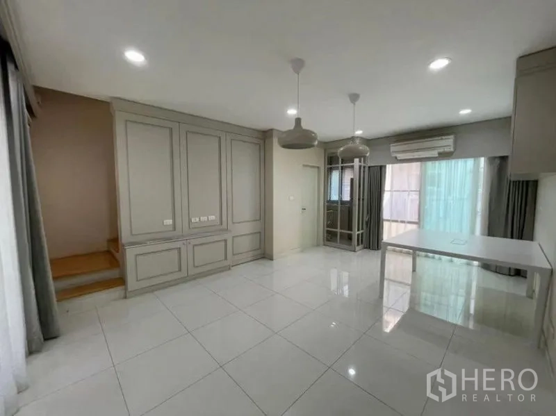 Townhouse for sale - Ground-floor living–dining space with staircase, air-conditioning, and sliding doors to the terrace.