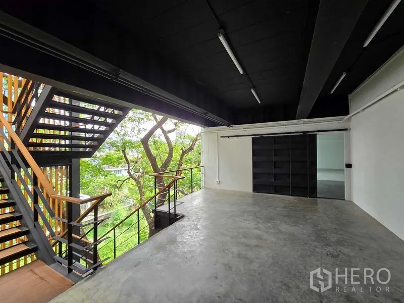 Home Office for rent in Chatuchak, Bangkok - Semi-open workspace with sliding door, black ceiling, and treetop outlook.