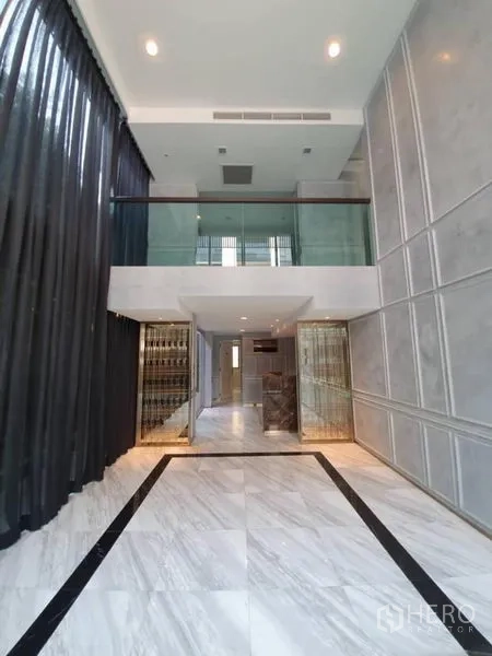 Office Space for rent in Khlong Toei, Bangkok - Double-height lobby with mezzanine glass balustrade and polished marble floors.