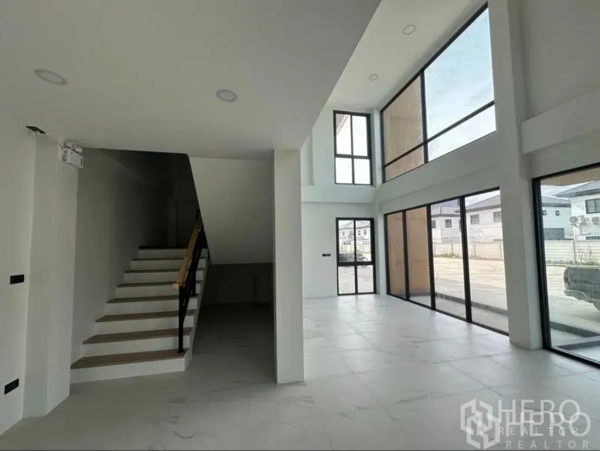 Warehouse for sale in Lam Luk Ka, Pathum Thani - Ground-floor office beside staircase with full-height glass walls facing the driveway.