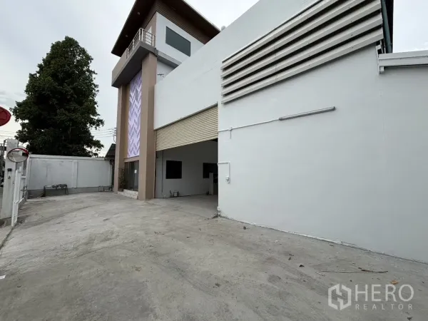 Warehouse for rent or sale in Wang Thonglang, Bangkok - Wide concrete yard with roller shutter access and corner office tower.