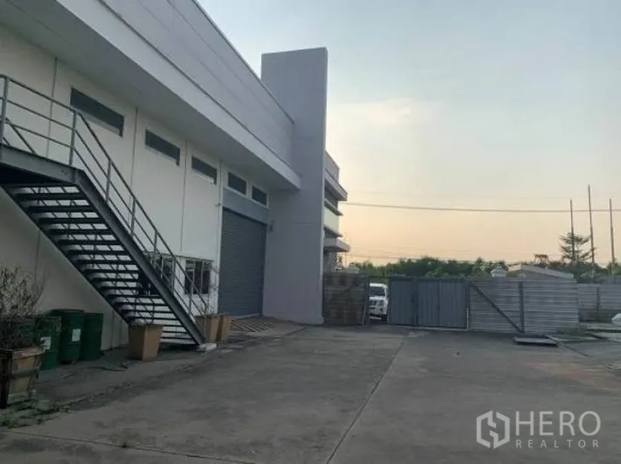 Factory for rent or sale in Wang Noi, Phra Nakhon Si Ayutthaya - Side of the factory with exterior stairway and a large roller shutter door.