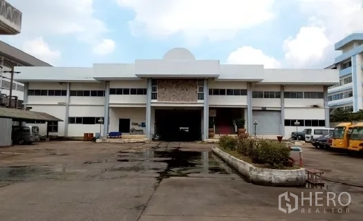 Factory for sale in Bang Phli, Samut Prakan - Two‑storey factory frontage with a central covered loading bay and wide driveway.