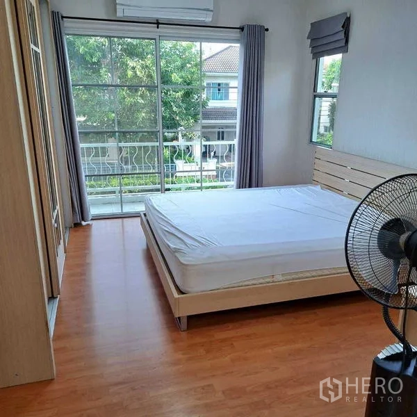 Detached House for rent in Prawet, Bangkok - Master bedroom with wood floors, balcony access, large window and air conditioner.