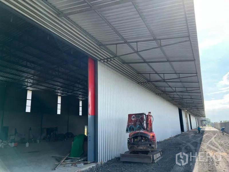 Warehouse for rent in Lam Luk Ka, Pathum Thani - Long metal-clad warehouse with covered loading bay and open high roller door in Lam Luk Ka.