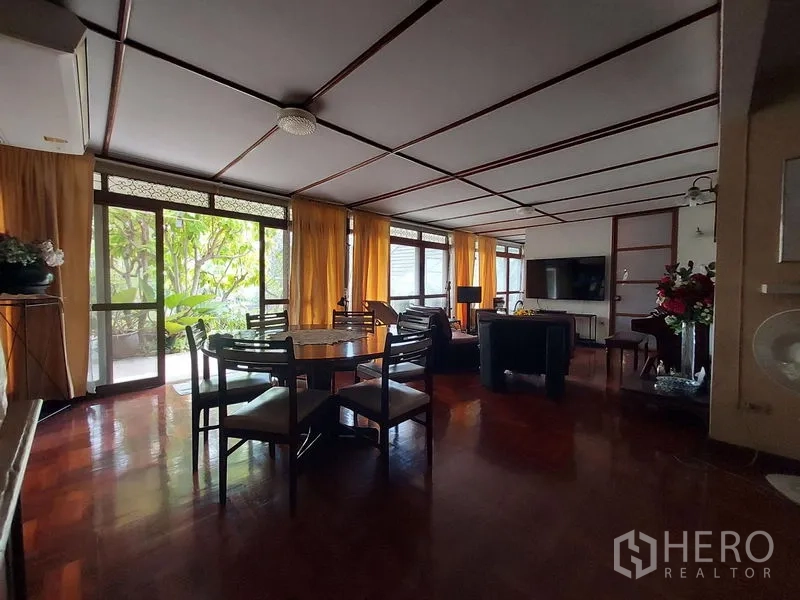 Detached House for rent in Mueang Samut Prakan, Samut Prakan - Open-plan dining and living area with a round table and wide glass doors to the patio.